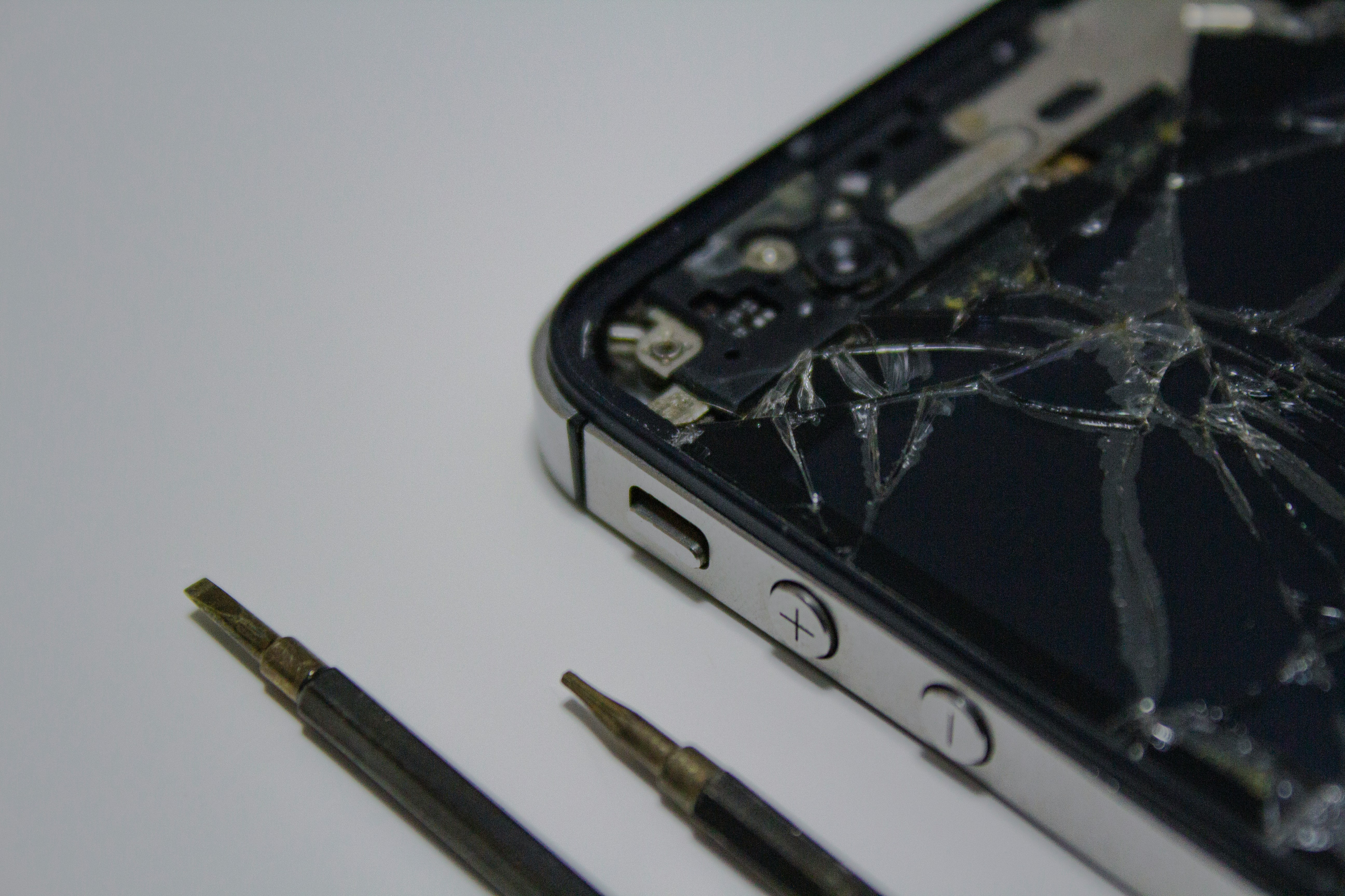 Close-up phone repair with cracked screen and tools